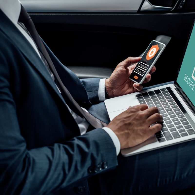 cropped-view-of-african-american-businessman-using-laptop-and-smartphone-in-car-with-cyber-security.jpg